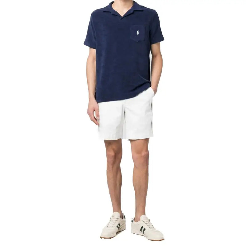 Polo shirt with white logo, navy blue color, short sleeves, and pocket detail.