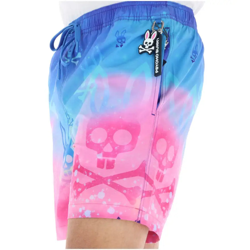 Psycho Bunny men swimwear blue and pink gradient swim trunks with skull and crossbones and white splatter accents