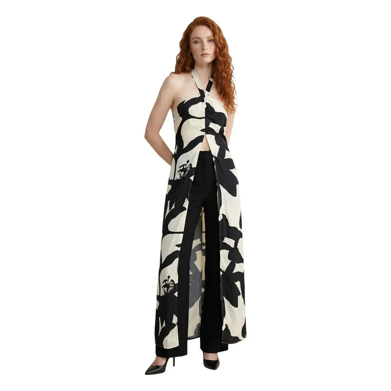 A woman wearing a replay women floral v neck strap summer dress white with black and cream halter top and wide-leg trousers