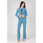 A woman wearing a tailored light blue Rinascimento turquoise blazer with button and lapel collar and matching flared trousers