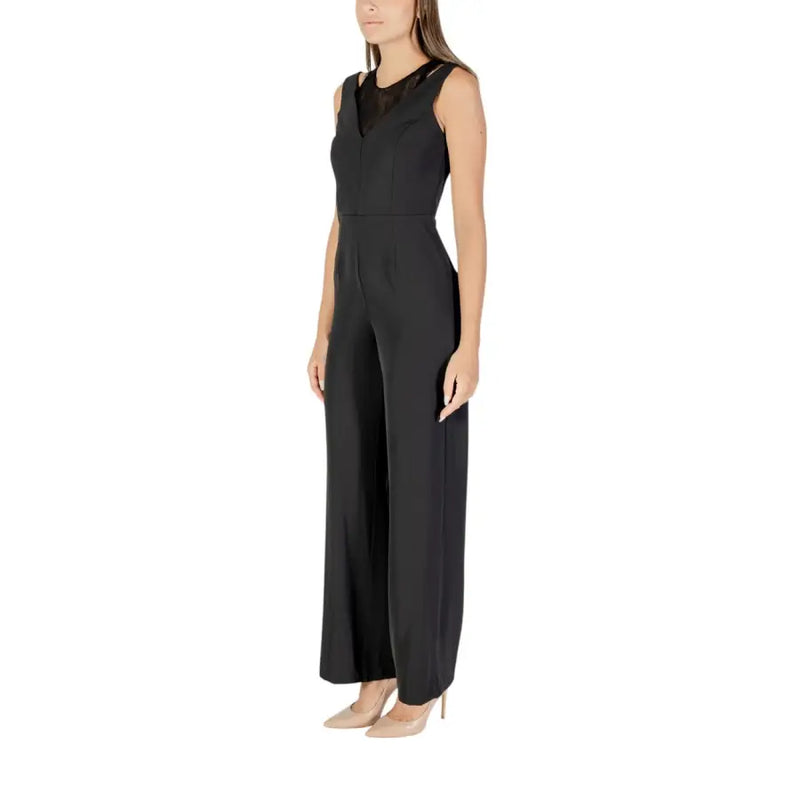 Women’s black sleeveless jumpsuit with V-neck and mesh insert paired with nude heels