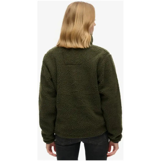 Woman wearing an olive green fleece jacket and dark pants from Superdry Women Knitwear Fall Winter collection