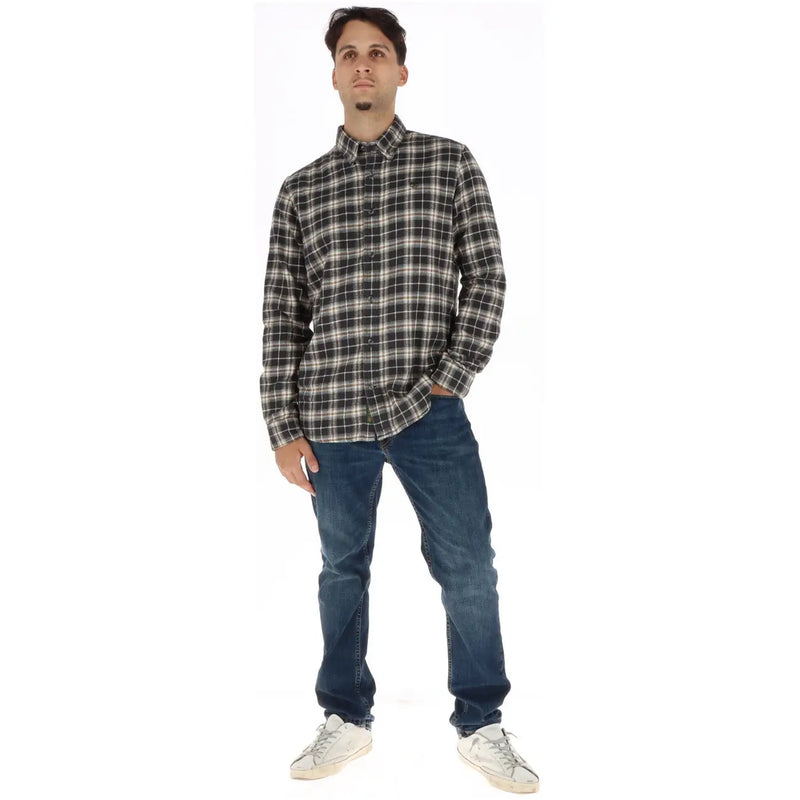 A man wearing a Timberland men checked cotton shirt black in black and white plaid paired with dark blue jeans