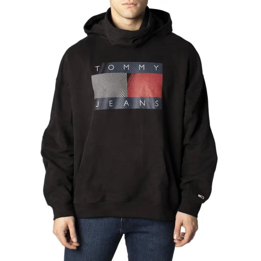 Tommy Hilfiger black hooded sweatshirt for men with bold graphic logo and gray red diagonal stripes on dark blue background