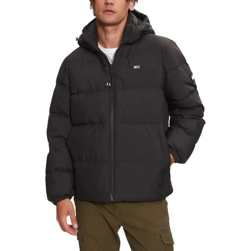 Schwarze Steppjacke mit Kapuze und Reißverschluss, wahrscheinlich aus synthetischem Material für optimale Wärme.
