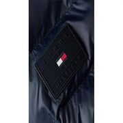 Black diamond-shaped tommy hilfiger patch with embossed logo and flag emblem on navy blue polyamide puffer jacket