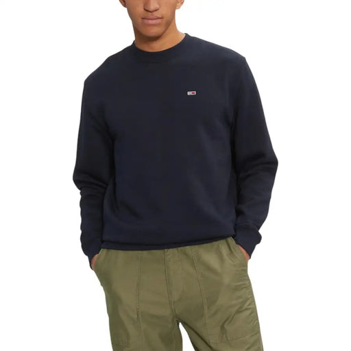 Men’s navy blue crew neck sweatshirt with flag logo on chest, paired with olive green pants