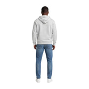 Ein Mann, der einen grauen Hoodie aus Bio-Baumwolle und blaue Jeans trägt Tommy Hilfiger Jeans Herrenkollektion