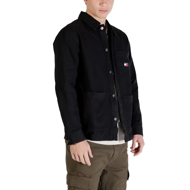 Schwarze Tommy Hilfiger Arbeitsjacke mit Knopfleiste, Brusttasche und dem ikonischen Flaggenlogo, das auch auf dem Tommy Hilfiger Jeanshemd für Herren zu sehen ist.