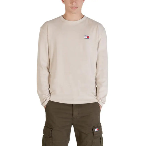 Beigefarbenes Tommy Hilfiger Jeans Herren-T-Shirt aus Bio-Baumwolle mit langen Ärmeln und gestickten Logos auf Brust und Cargotasche.