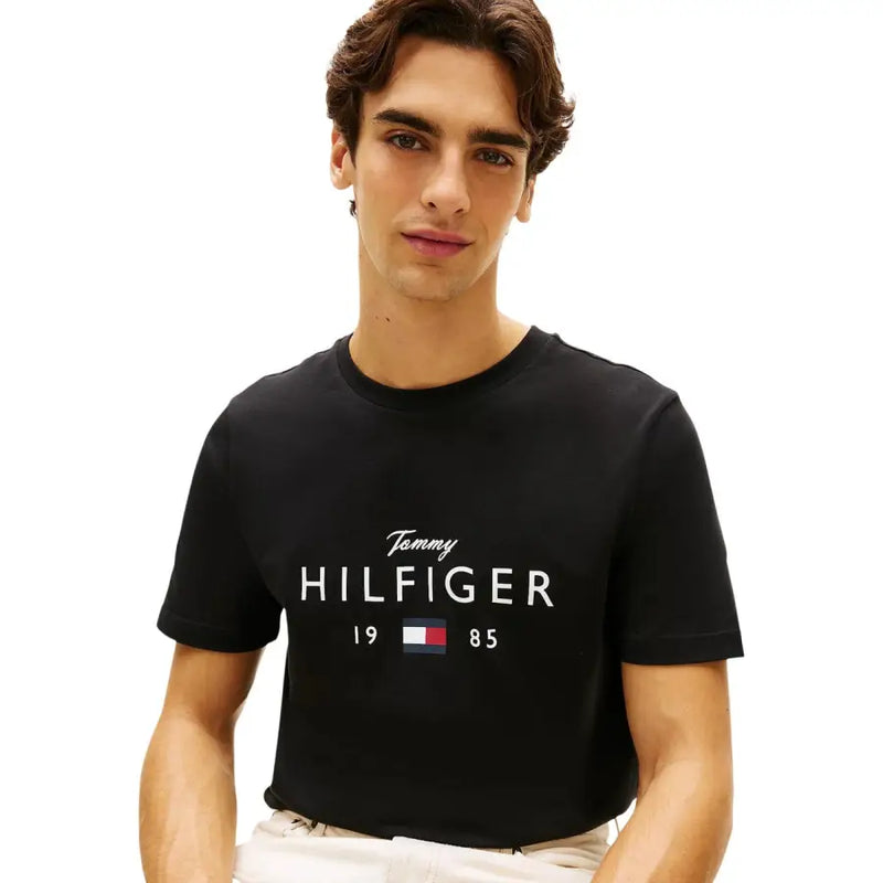 Schwarzes Baumwoll-T-Shirt von Tommy Hilfiger mit weißem Tommy Hilfiger 1985-Logo und Flaggenemblem-Aufdruck