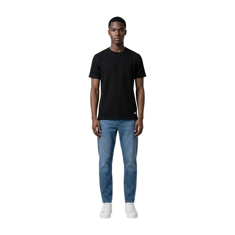 Black short-sleeved crew neck cotton t-shirt with small red and white logo on lower left side by Tommy Hilfiger Jeans