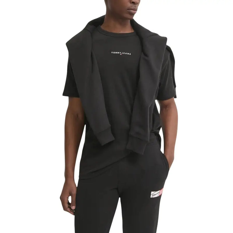 Schwarzer Tommy Hilfiger Jeans-Hoodie über passendem schwarzem T-Shirt und Hose mit dezentem weißen Brustlogo.