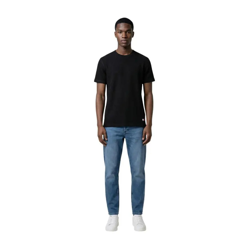 T-shirt noir à manches courtes et col rond en coton t-shirt avec un petit logo rouge et blanc en bas à gauche par Tommy Hilfiger Jeans