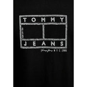 Noir Tommy Hilfiger jeans hommes t-shirt avec le logo Tommy Jeans NYC 1985 en lettres capitales grasses, style tableau noir blanc