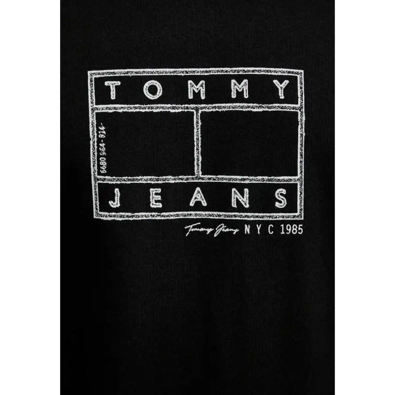 Noir Tommy Hilfiger jeans hommes t-shirt avec le logo Tommy Jeans NYC 1985 en lettres capitales grasses, style tableau noir blanc