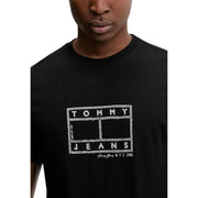 Noir Tommy Hilfiger jeans hommes t-shirt avec le logo Tommy Jeans NYC 1985 en blanc craie sur le devant