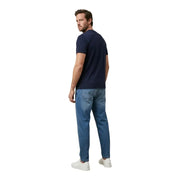 A man wearing a navy blue short-sleeved tommy hilfiger t-shirt and medium-wash denim jeans for men