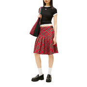 Roter Faltenrock mit Karomuster und grünen und schwarzen Akzenten, kombiniert mit einer schwarzen Tommy Hilfiger Jeans aus Bio-Baumwolle für Damen. t-shirt