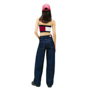 A woman wearing dark blue wide-leg organic cotton tommy hilfiger jeans with logo on back waistband and a pink cap