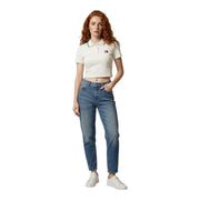 A woman wearing a white cropped polo shirt with black trim and Tommy Hilfiger logo paired with medium wash jeans