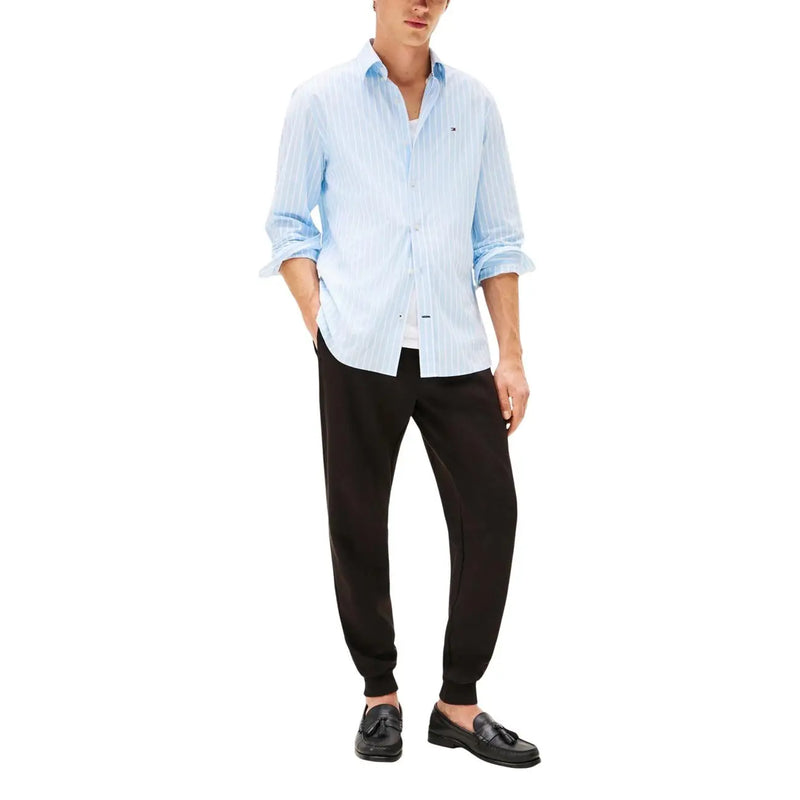 Light blue and white vertically striped cotton button-down shirt with rolled-up sleeves paired with tommy hilfiger men black cotton trousers