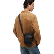 Black calvin klein crossbody bag with textured leather and sleek minimalist design shown from the back side
