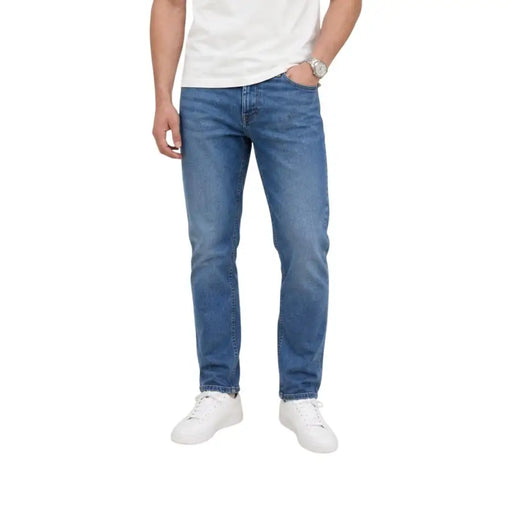 Medium-wash blue cotton denim jeans for men with slim taper fit and classic five-pocket design by Tommy Hilfiger