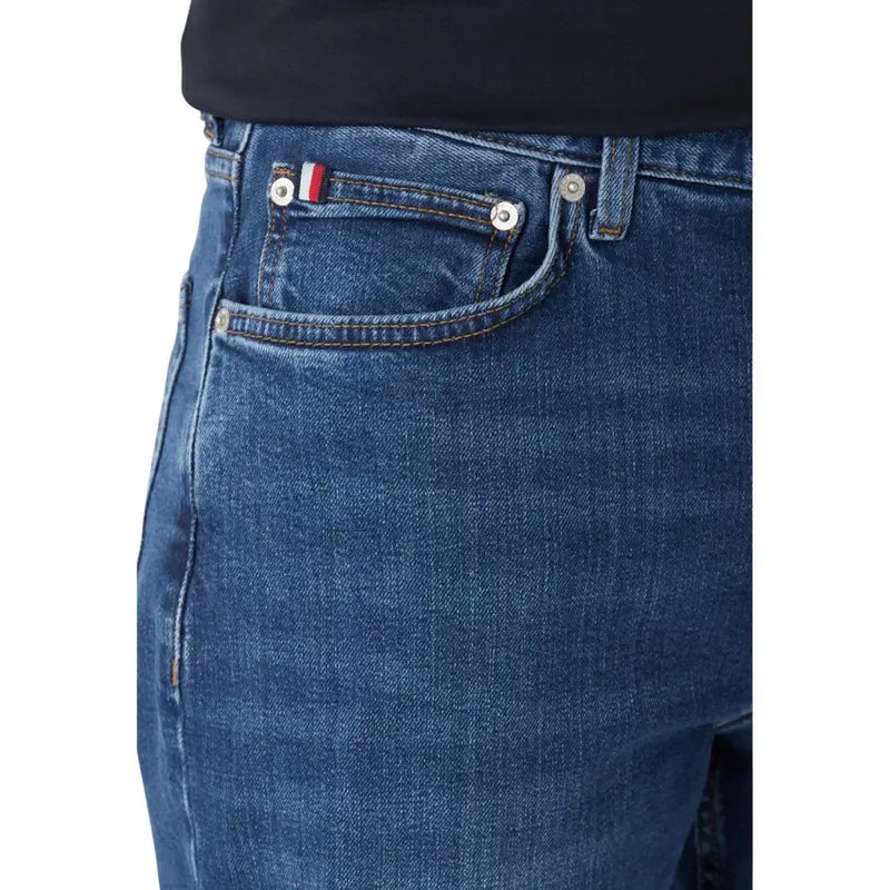 Dunkelblaue, schmal geschnittene Jeans aus Bio-Baumwolle mit silbernen Knöpfen und einem Flaggenaufnäher auf der Gesäßtasche.