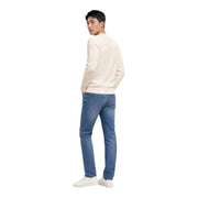Ein Mann, der einen cremefarbenen Tommy Hilfiger Weißer Rundhals-Strickpullover aus Bio-Baumwolle kombiniert mit blauen Jeans