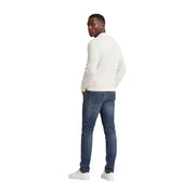 A man wearing tommy hilfiger men scanton slim blue jeans cotton paired with a cream-colored long-sleeved knit sweater