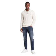 Cream-colored tommy hilfiger polo sweater with classic collar and buttoned front paired with slim blue cotton jeans