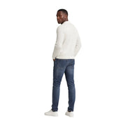 A man wearing tommy hilfiger men scanton slim blue jeans cotton paired with a cream-colored long-sleeved knit sweater