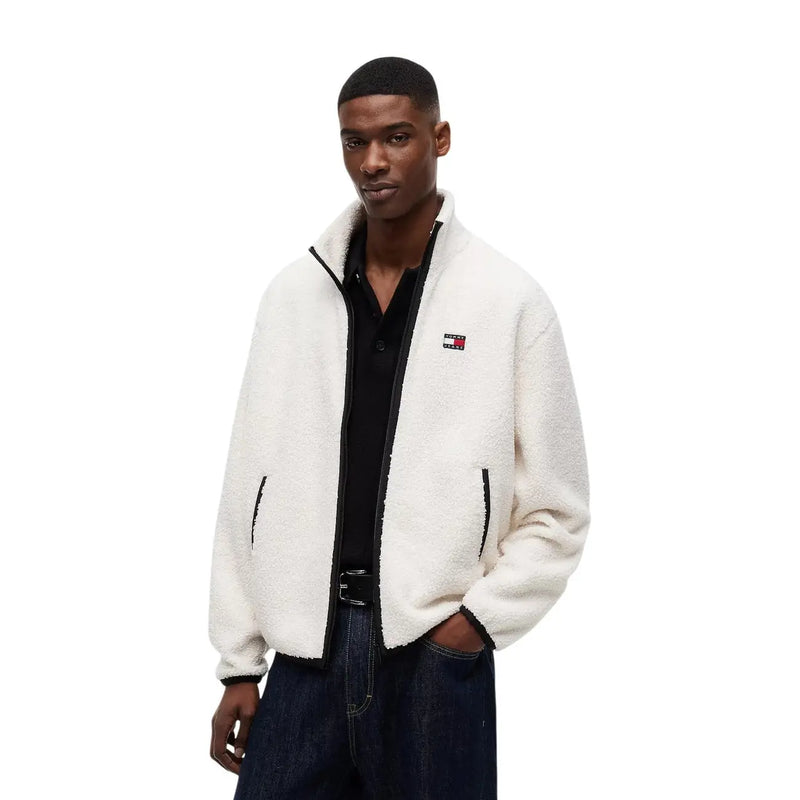 White fluffy fleece jacket with black zipper and trim featuring tommy hilfiger logo on left chest in polyester
