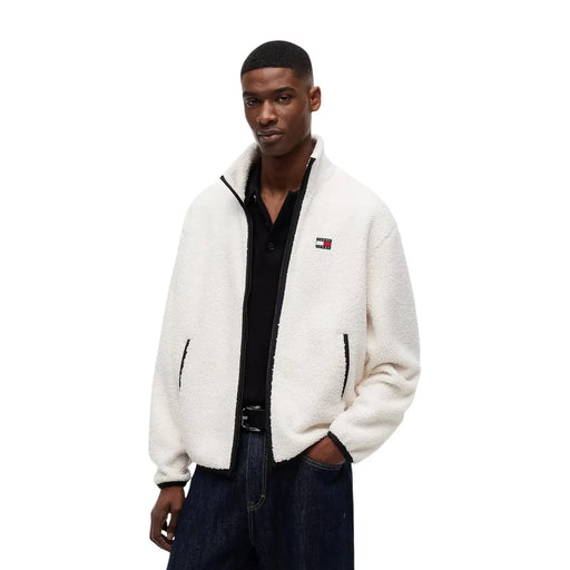 White fluffy fleece jacket with black zipper and trim featuring tommy hilfiger logo on left chest in polyester