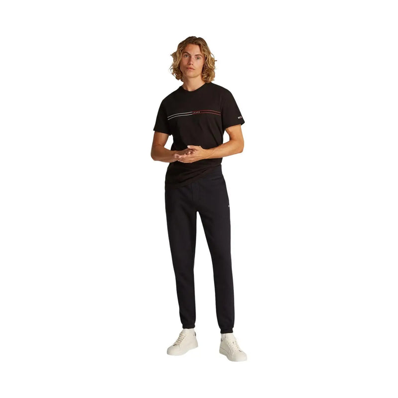 Tommy hilfiger men black slim cotton fleece trousers paired with a black t-shirt with white and pink stripes