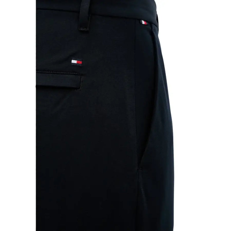 Schwarze Tommy Hilfiger Herrenhose mit dezenter Webstruktur und dem charakteristischen rot-weiß-blauen Logo am Bund und an der Tasche.