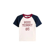 Cream-colored tommy hilfiger miss tommy 85 raglan organic cotton tee with navy sleeves maroon collar and glittery red lettering