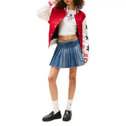 Young woman wearing a varsity jacket, crop top, denim skirt, socks, and loafers