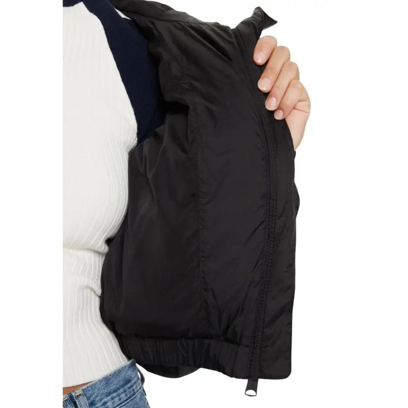 Woman wearing Tommy Hilfiger black nylon jacket with hood and turtleneck, white top, and blue jeans