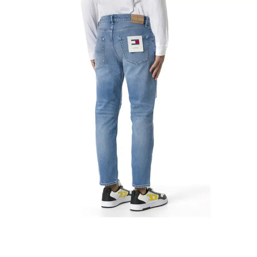 Back side of light-wash tommy jeans men blue cotton stretch jeans featuring classic tommy hilfiger logo patch