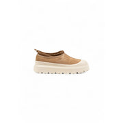 Beige Ugg Wildleder-Slipper für Herren mit cremefarbener, klobiger Sohle und Ugg-Logo – ideal für den Winter.