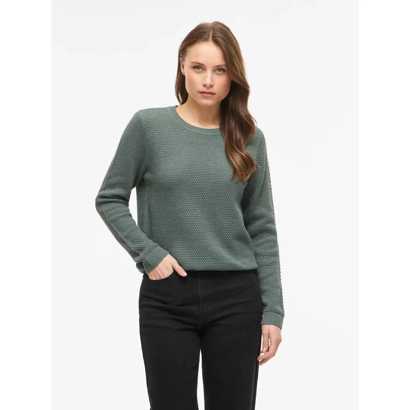 Schwarzes, langes Baumwollstrickoberteil von Vila mit Rundhalsausschnitt, kombiniert mit einem olivgrünen, strukturierten Strickpullover mit Rippbündchen.