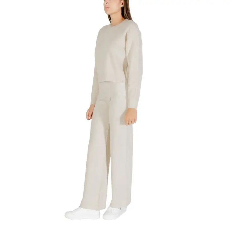 Cream-colored knit sweater with long sleeves and round neck paired with matching wide-leg knit trousers for women