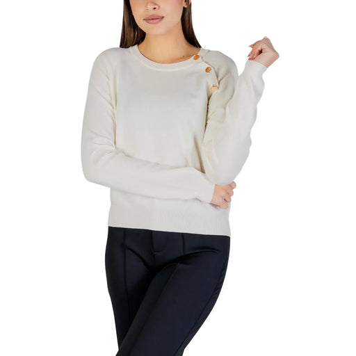 Cream-colored knit sweater with wooden shoulder buttons, white long sleeve top