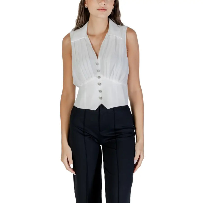 White sleeveless V-neck zip top with pointed hem paired with black trousers for fall winter fashion