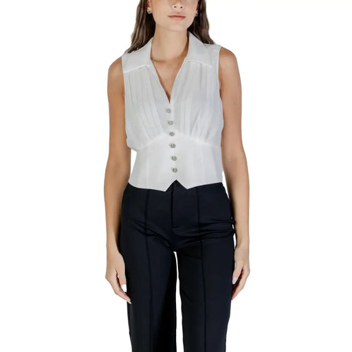 White sleeveless V-neck zip top with pointed hem paired with black trousers for fall winter fashion