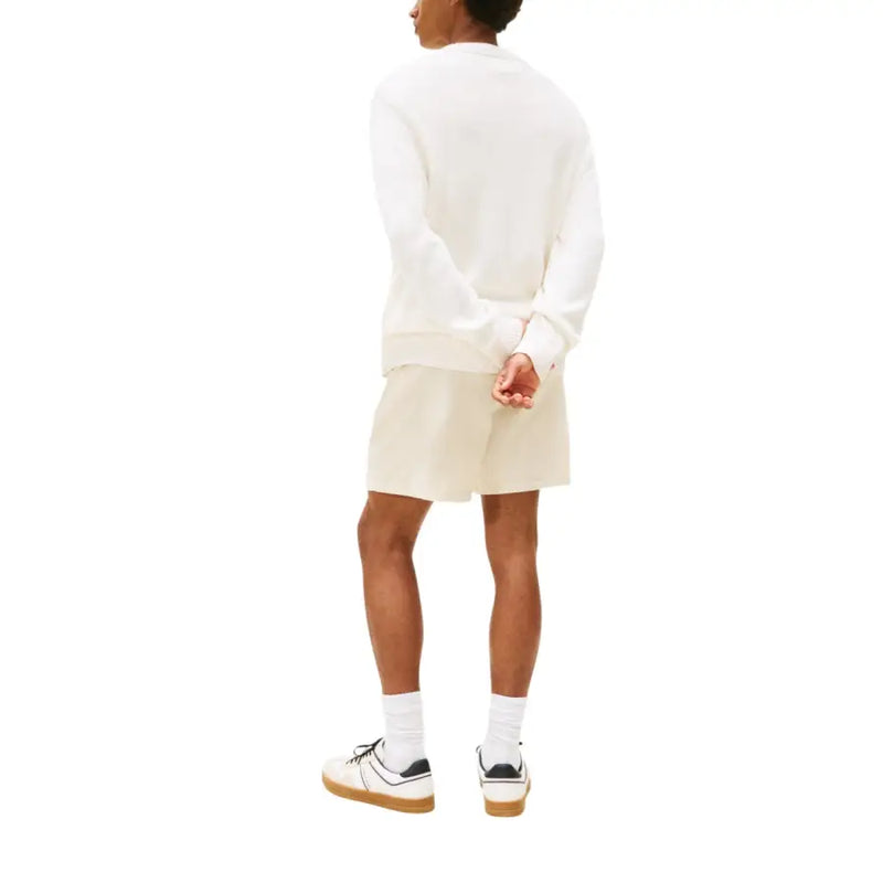 A cream-colored long-sleeved sweatshirt with a relaxed fit and ribbed cuffs featuring a red logo