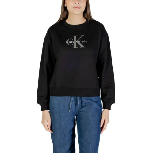 Femme portant du noir Calvin Klein sweat-shirt à manches longues et pantalon en jean bleu à cordon.