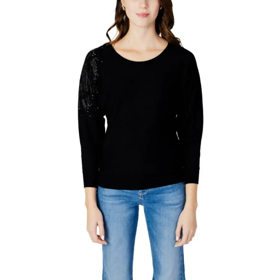 
                      
                        Guess women knitwear, model in Guess black top and jeans posing stylishly
                      
                    